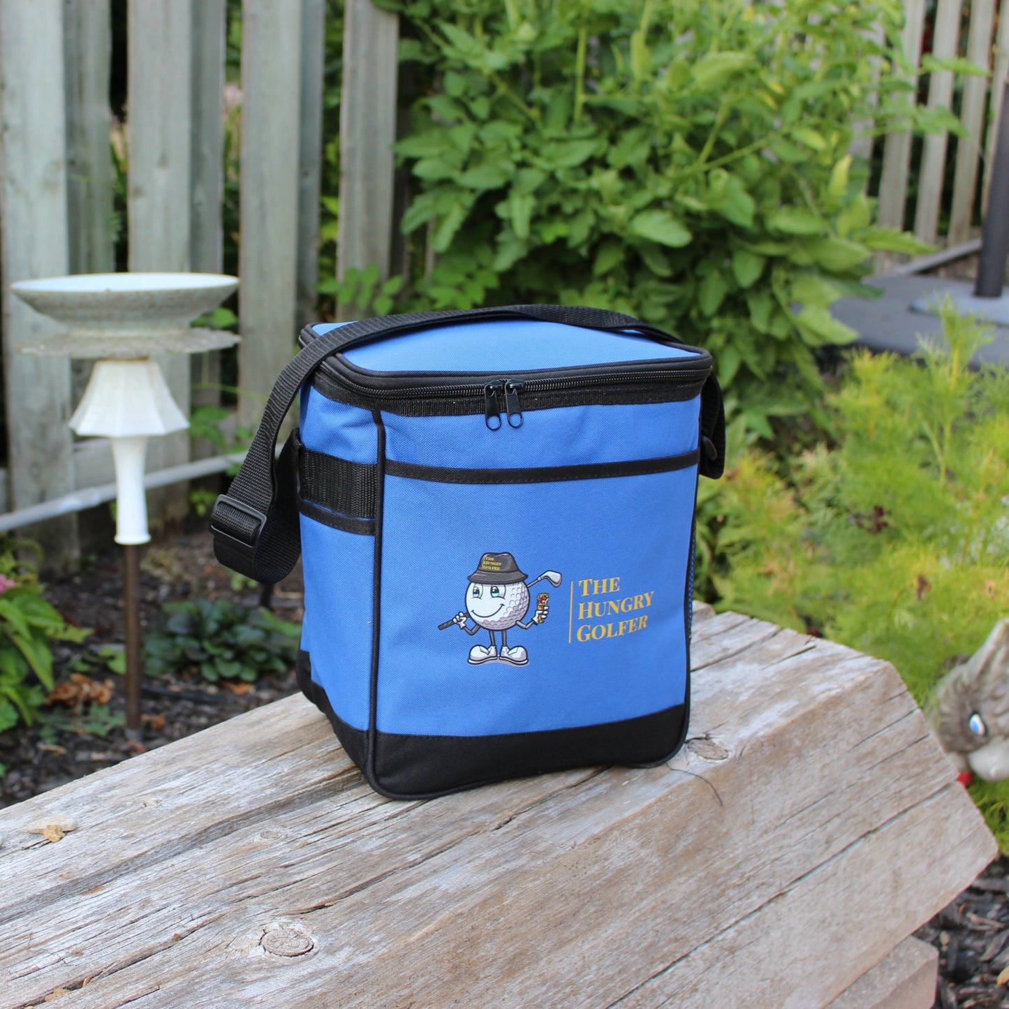Blue cooler bag with a cartoon character on a wooden log outdoors