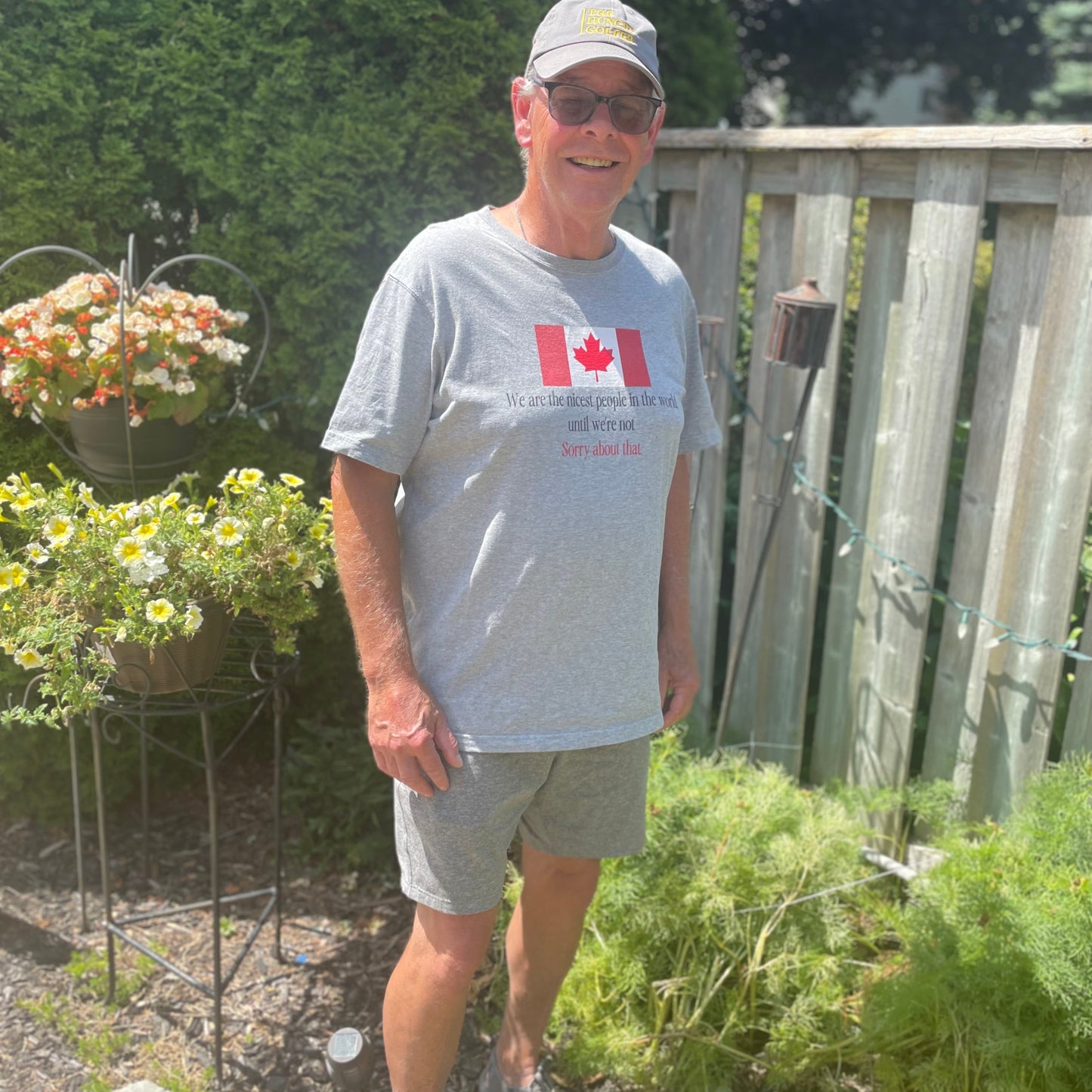 Man wearing a gray t-shirt with a Canadian flag design, standing in a garden.